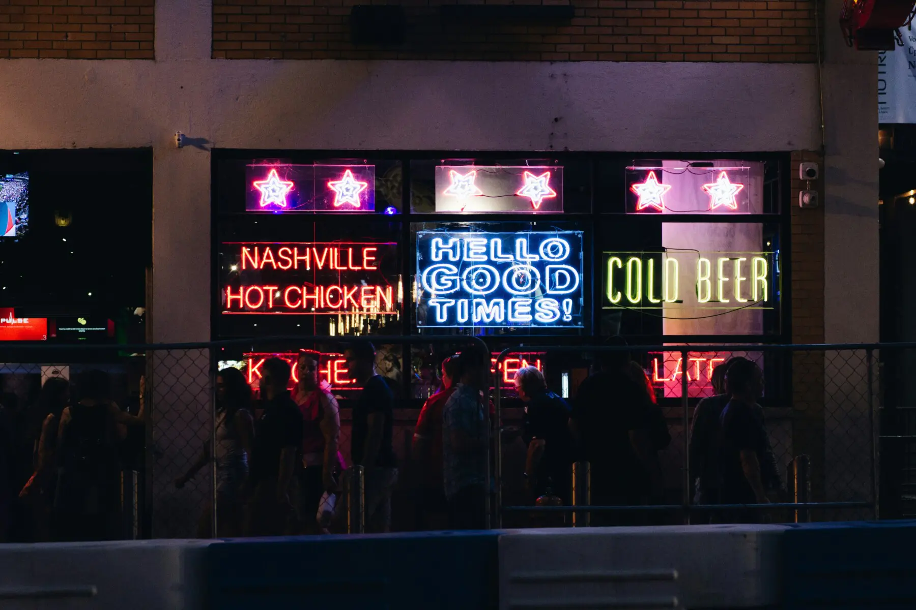 Group of people in front of neon signs on Nashville Broadway at night