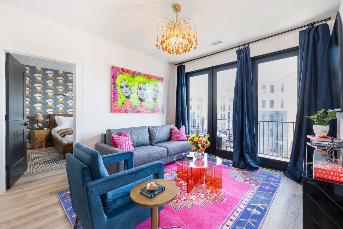 Music City Magnolia property living room — Dolly Parton art, pink rug, blue velvet chair