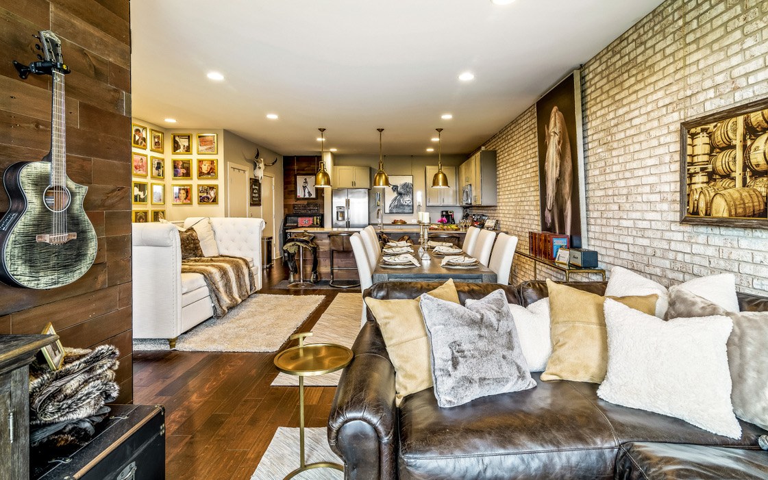 Music City Magnolia Nashville vacation rental living room with exposed brick, leather sofa, guitar on wall