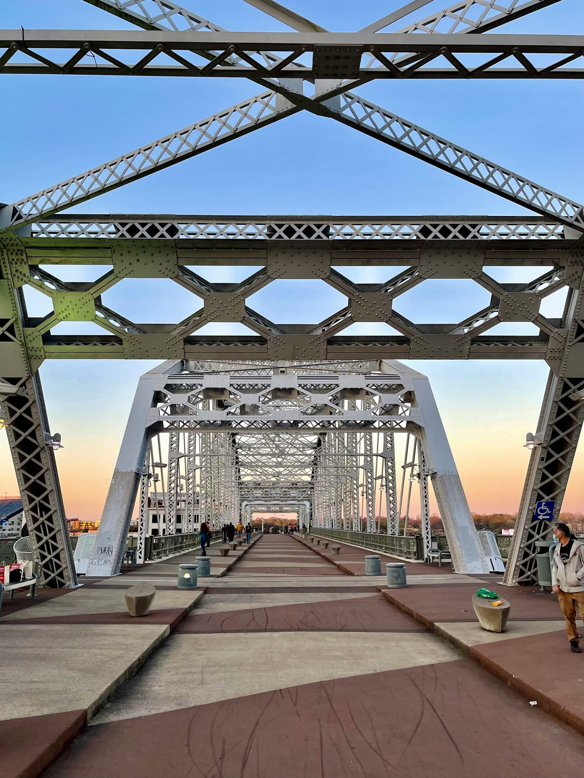 People walking across the John Seigenthaler Pedestrian Bridge toward Nashville honky-tonks