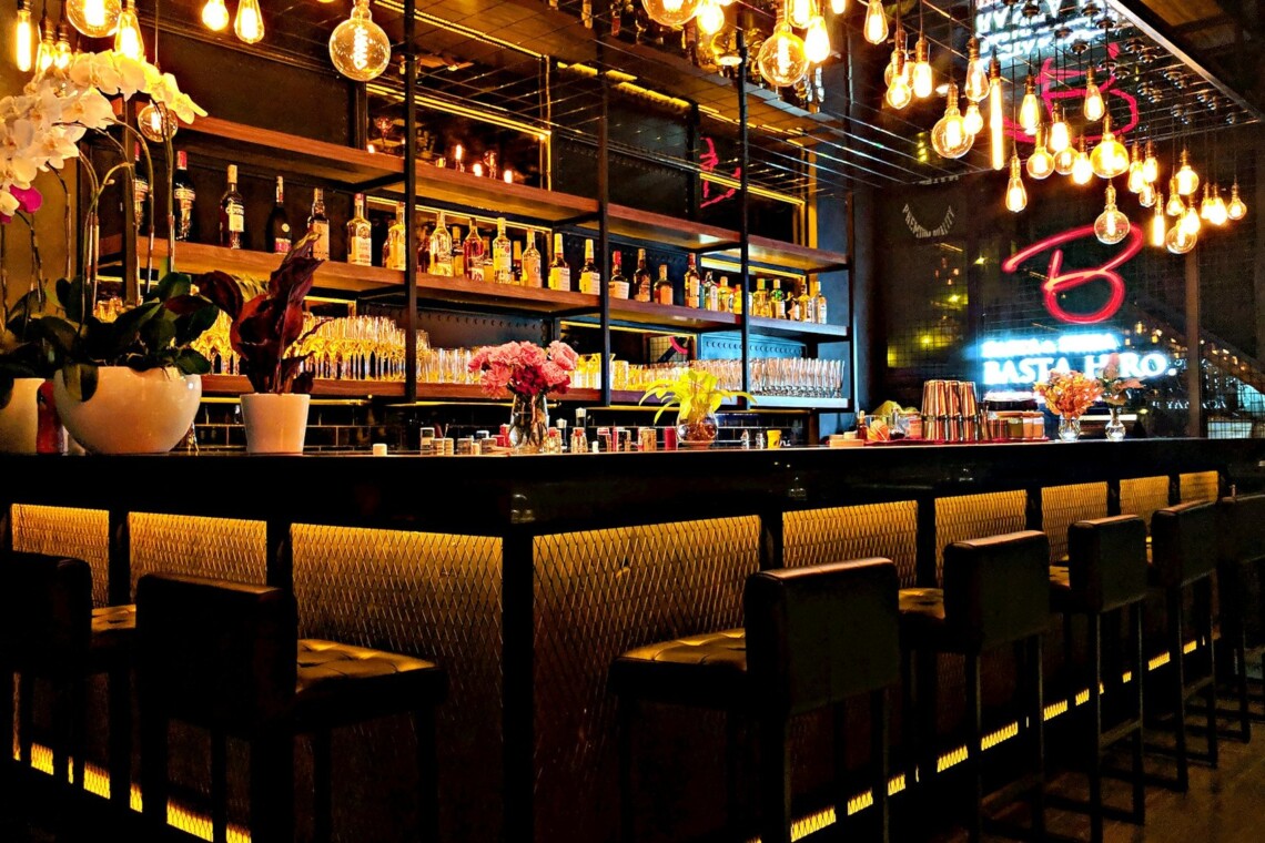 A warm neighborhood cocktail bar with Edison bulbs, orchids, and a full backbar - the vibe of a real Nashville happy hour
