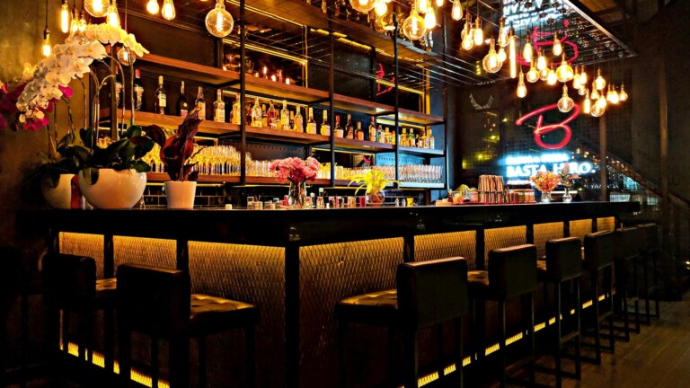 A warm neighborhood cocktail bar with Edison bulbs, orchids, and a full backbar - the vibe of a real Nashville happy hour