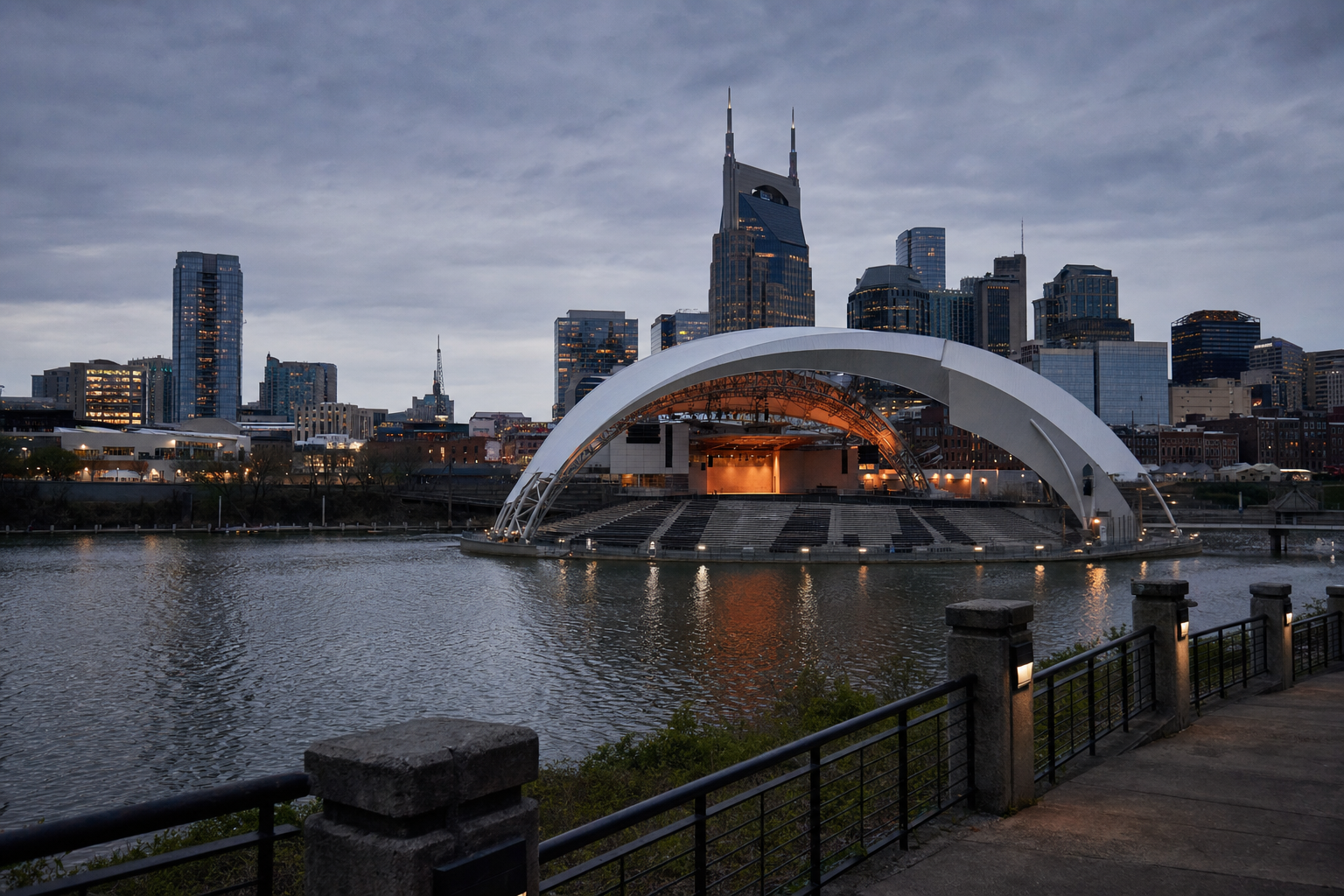 Ascend Amphitheater curved white canopy roof against the downtown Nashville skyline including the AT&T twin-spired tower, viewed from across the Cumberland River